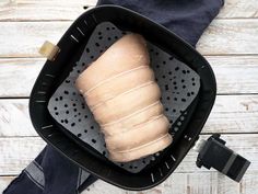 a loaf of bread sitting in a black basket on top of a wooden table next to a pair of jeans