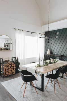 a dining room table with black chairs and a white rug in front of the window