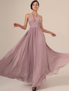 a woman in a long purple dress with her arms out and one hand on her hip