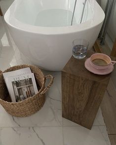 a bath tub sitting on top of a white tiled floor next to a magazine holder