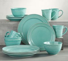 a set of turquoise colored dishes and cups