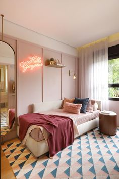 a bedroom with pink walls and a white bed in the corner, next to a large mirror