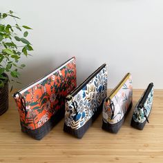 three purses sitting on top of a wooden table next to a potted plant