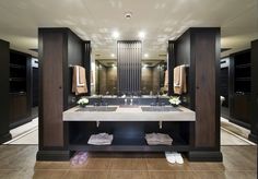 a large bathroom with two sinks, mirrors and towels on the rack in front of it