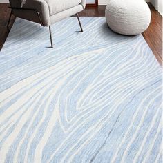 a blue and white rug in a living room next to a gray chair with a pillow on it