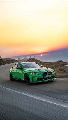 a green sports car driving on a road at sunset or dawn with the sun in the background