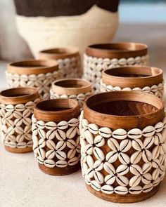 several wooden vases with shells in them on a table next to a potted plant