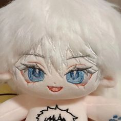 a close up of a stuffed animal with white hair and blue eyes