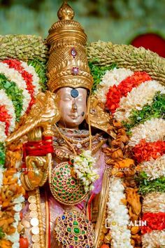 a statue of the hindu god person in front of flowers and garlands on display