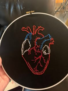 a hand embroidered heart on a black circle with red, white and blue stitching