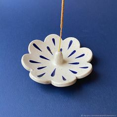 a white ceramic flower ornament hanging from a string on a blue tablecloth