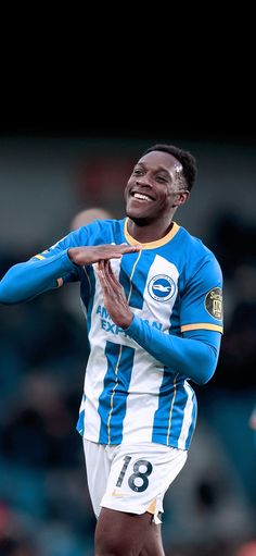 a man in blue and white soccer uniform holding his arms out to the side while smiling