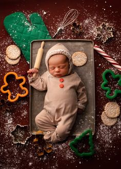 a baby is laying in a pan with cookies and pretzels