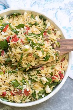 a white bowl filled with pasta and veggies on top of a blue table cloth