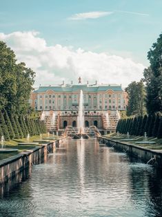 a large building sitting on top of a lush green field next to a lake filled with water