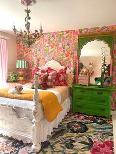 a bedroom decorated in pink, yellow and green with a floral wallpaper on the walls