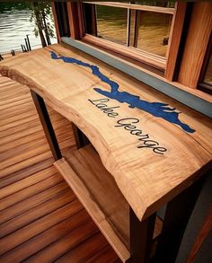 a wooden bench sitting on top of a wooden floor next to a window with the words lake george written on it