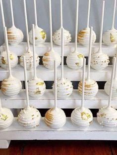 white and gold cake pops lined up on a rack