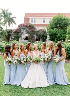 a group of bridesmaids standing together in front of a house with their bouquets