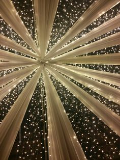 the ceiling is decorated with white lights and drapes in an open space that looks like a starburst