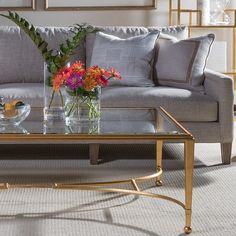 a living room filled with furniture and flowers on top of a glass table in front of a couch