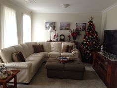 a living room filled with furniture and a christmas tree in the corner on the wall