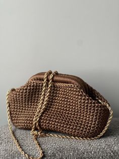 The elegant crochet clutch with inside clasp (+ lining and chain) Material: Crafted from high-quality yarn, ensuring a soft and durable texture. Color: Copper. Size: The clutch measures 22 cm at the base (clasp is 15 cm), providing ample space for your daily essentials. Closure: Features a premium-quality kiss lock frame (clasp), keeping your belongings secure. Customizable Hardware: Available for made-to-order clutches, allowing you to choose from gold, silver, antique, or dark (black) nickel hardware. A matching chain in the selected hardware color is included with every clutch. Care Instructions: To keep your clutch looking its best, avoid washing. We recommend spot cleaning any stains or opting for professional dry cleaning. Chic Crochet Bag With Chain Strap For Everyday, Elegant Woven Crochet Crossbody Bag, Beige Crochet Evening Bag, Elegant Brown Crochet Bag For Daily Use, Handmade Beige Crochet Bag For Evening, Elegant Handmade Crochet Crossbody Bag, Chic Crochet Bag For Evening, Elegant Crochet Evening Bag With Removable Pouch, Elegant Beige Crochet Crossbody Bag