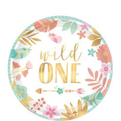 a paper plate with the words wild one in gold foil on it, surrounded by flowers and leaves