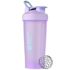 the blender bottle has a purple lid and is next to a whisk