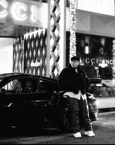 a man standing next to a parked car in front of a building