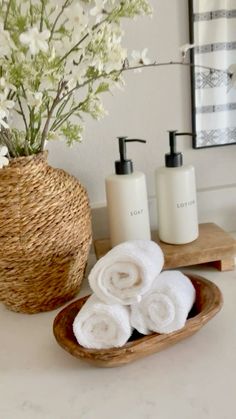 towels and soaps in a basket on a bathroom counter with a vase full of flowers