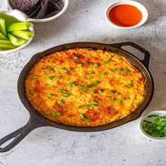 an omelet in a cast iron skillet with green onions and sauces