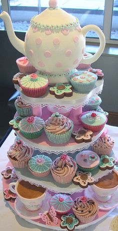 cupcakes and muffins are stacked on top of each other in front of a teapot