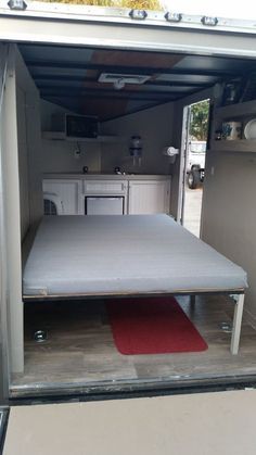 the inside of a camper with its door open and mattress on it's side