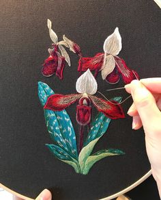 a person is stitching flowers on a piece of fabric