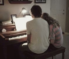 two people sitting at a piano playing music