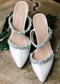 the bride's white shoes are adorned with swaro - cut crystals and greenery