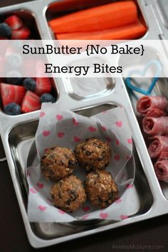 an open lunch box filled with fruit and veggies, including carrots, blueberry muffins and strawberries