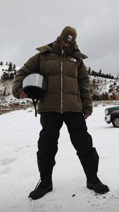 a man standing in the snow with his helmet on