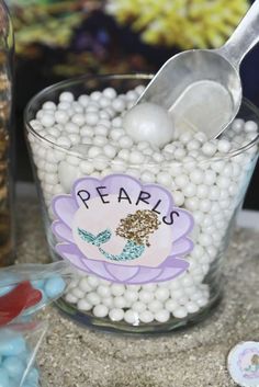 a glass filled with lots of white beads and plastic spoons on top of a table