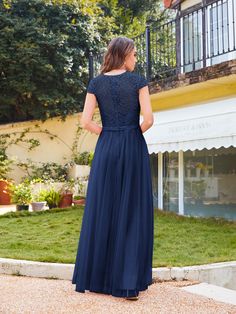 a woman in a long blue dress standing outside