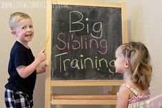 two young children standing in front of a blackboard with the words big sibling training written on it