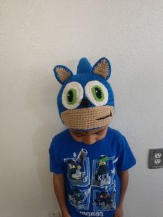 a young boy wearing a crocheted blue hat with big eyes and an angry face