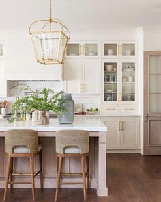 a kitchen with two stools at the center of the counter and an island in front of it