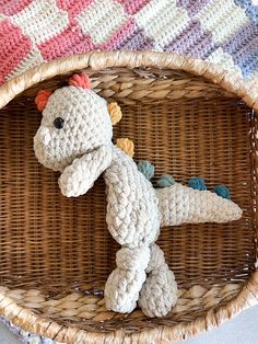 a crocheted stuffed animal laying on top of a wicker basket next to a blanket