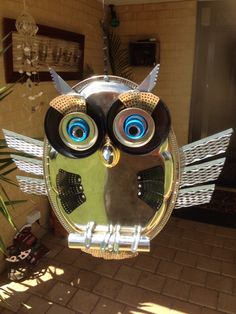 an owl shaped mirror hanging from the side of a building