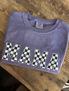 a purple shirt with black and white checkered letters on the front that says mia