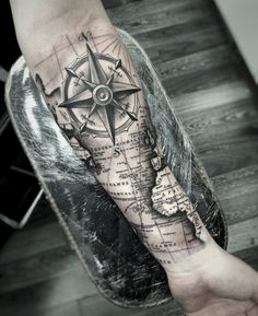 a man's arm with a compass and map tattoo on the left inner forearm