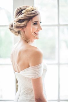 a woman in a white dress is standing near a window and smiling at the camera