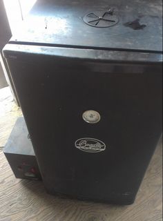 a black refrigerator sitting on top of a wooden floor